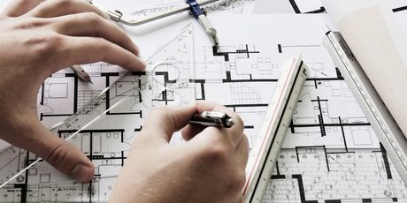 Hände mit Zirkel und Stift über einem Grundrissplan